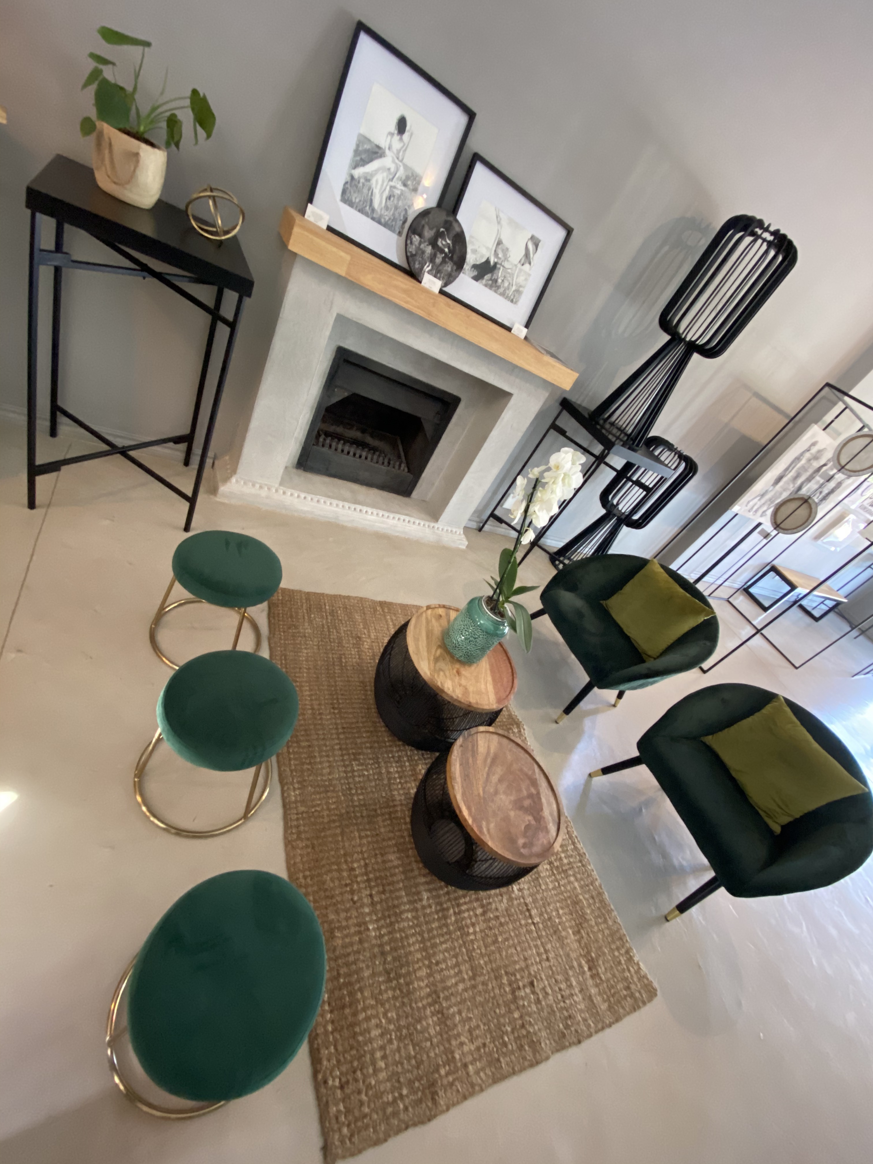 Modern lounge with fireplace, green chairs, round stools, and decorative wall art