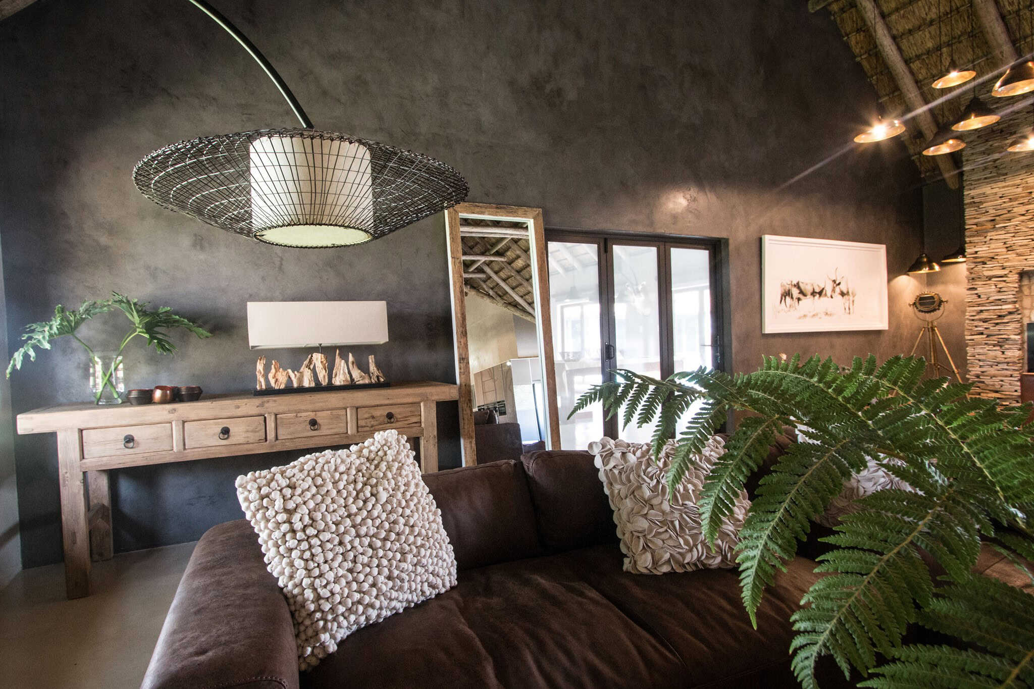 Stylish living room with dark accent wall, rustic wooden furniture, and plants