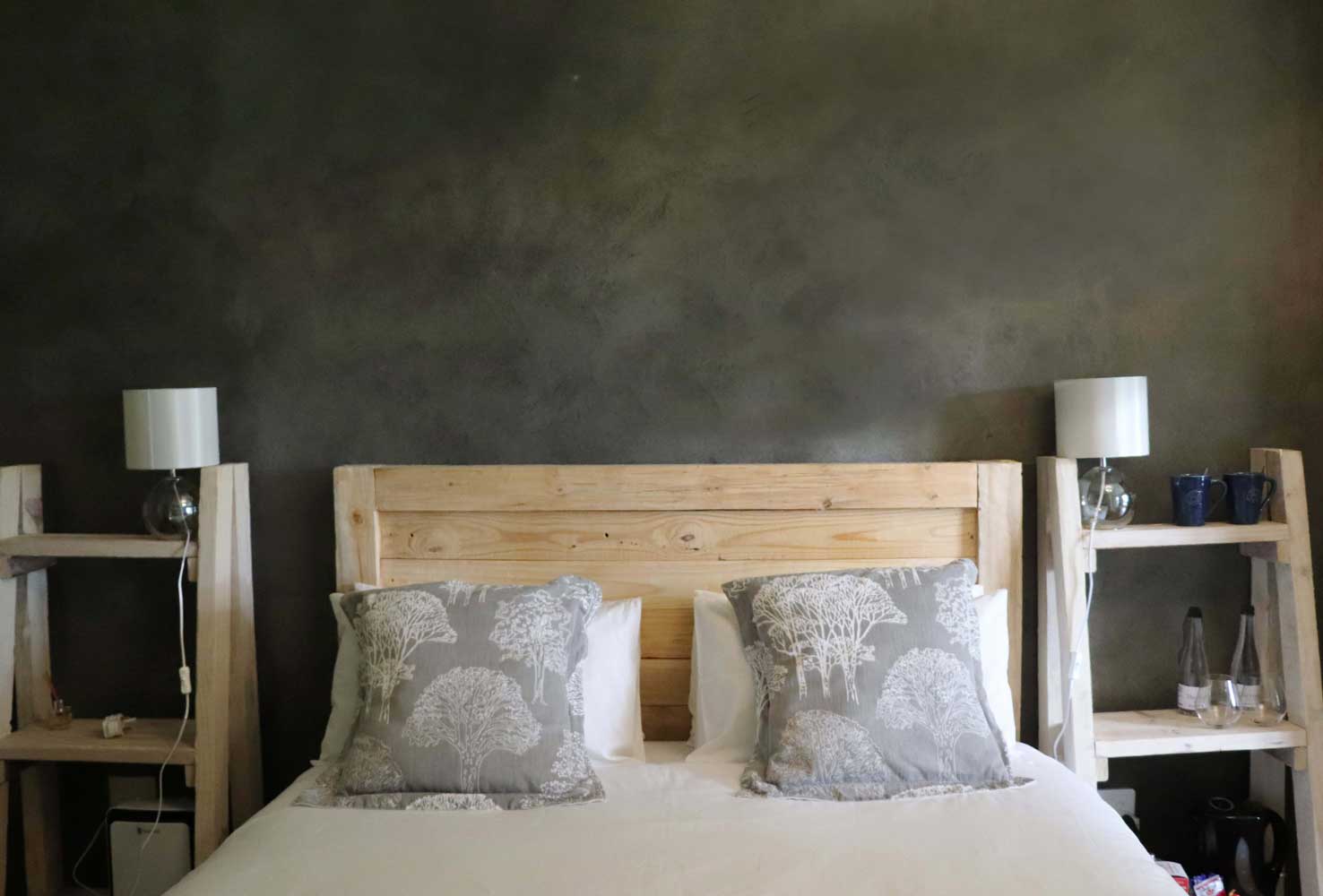 Minimalist bedroom with wooden headboard and grey feature wall