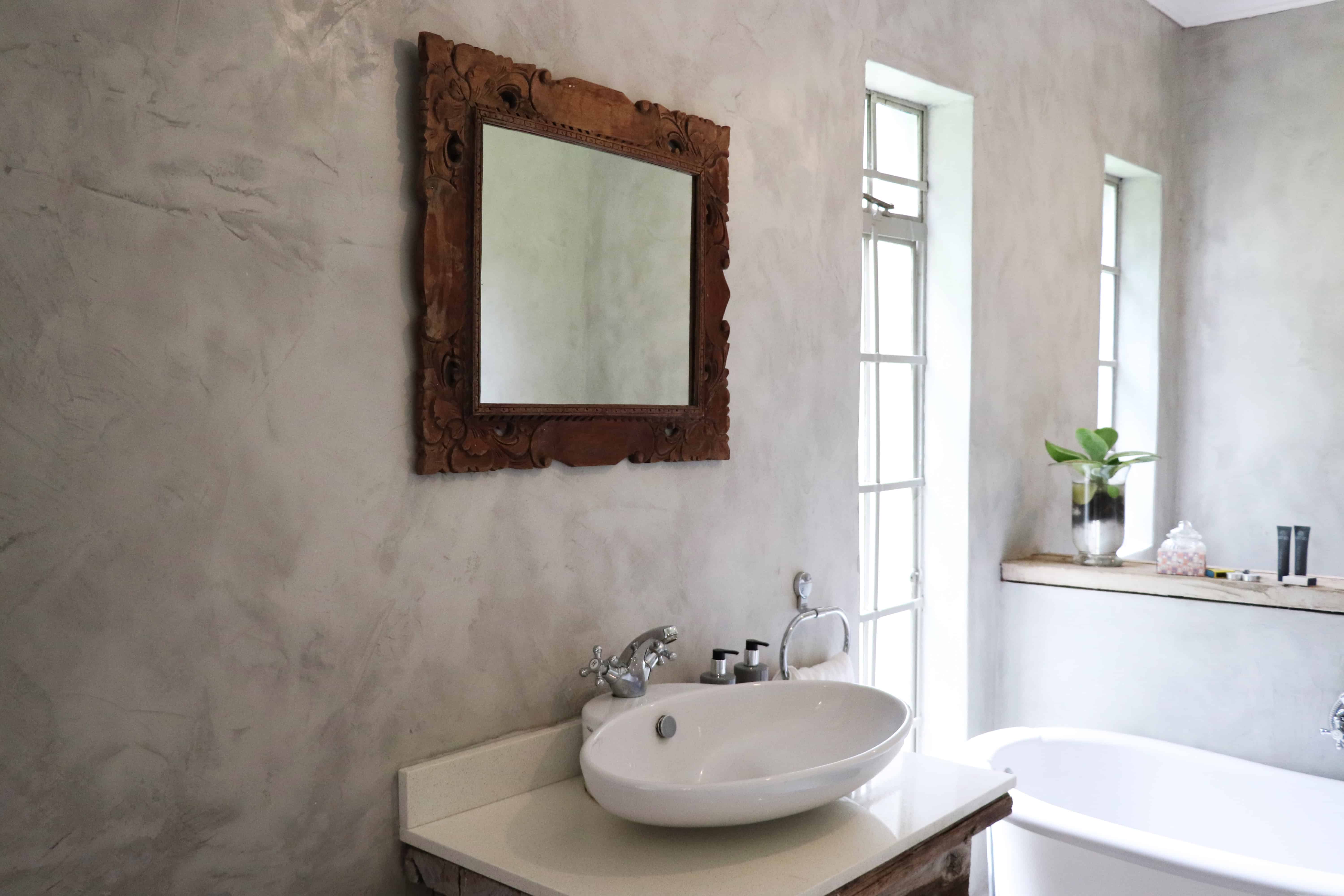 Bright bathroom with carved wooden mirror and white freestanding bathtub