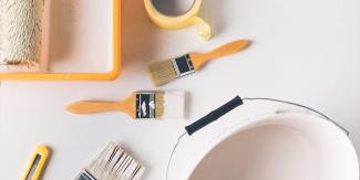 Paint brushes, roller, tape, and bucket ready for painting