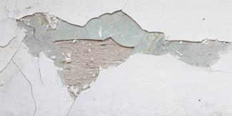 Close-up of peeling wall paint showing surface damage